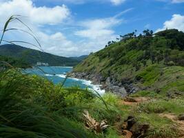 luftaufnahme von meereswellen, die auf einer felsenklippe im blauen ozean zusammenstoßen. Blick von oben auf die Küstenfelsen im Ozean von Phuket. landschaftsaussichtspunkt von laem phromthep cap am morgen. foto