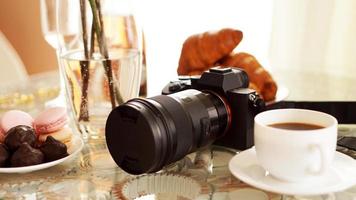 Fotokamera mit Objektiv auf Glastisch. Tasse Kaffee foto