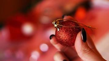 weibliche Hand hält roten Ball auf Weihnachtshintergrund foto