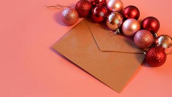 Umschlag aus Bastelpapier mit weihnachtlichen roten und rosa Kugeln auf rosa foto