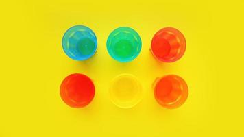 Plastikglas in verschiedenen Farben auf gelbem Hintergrund isoliert foto