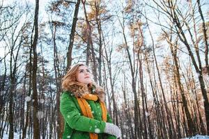 Mädchen in einer Winterjacke und Fäustlingen auf einem Waldhintergrund foto