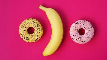 gelbe Banane und Donuts auf rosa Hintergrund. obige Ansicht foto