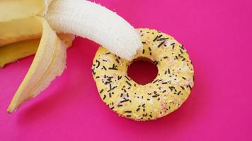 süßer Donut und Banane auf rosafarbenem Hintergrund. erotisches Konzept foto