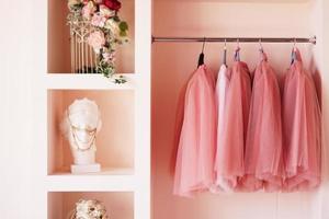 Ankleideschrank mit rosa Kleidern auf Kleiderbügel foto