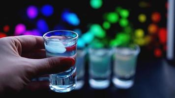 weibliche Hand mit einem Schuss Alkohol, Neon verschwommener Hintergrund foto