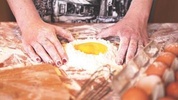 professionelle Bäckerin, die Teig mit Eiern und Mehl kocht foto