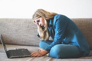 müde Frau sitzt mit Laptop, fauler Student macht Hausaufgaben foto