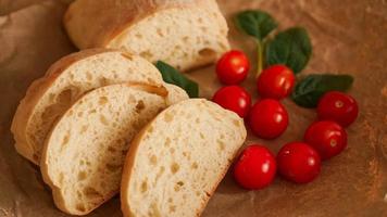 Ciabatta-Scheiben und Kirschtomaten auf Kraftpapier. foto