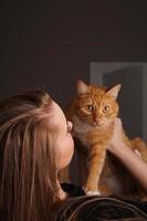 schöne junge Frau mit einer flauschigen roten Katze foto