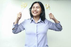 heiter asiatisch jung Frau halten Kerzen Nummer 2024 zu feiern Neu Jahre Vorabend Party tragen grau Hemd foto