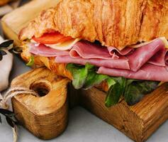 köstlich Croissant Sandwich auf hölzern Tafel foto