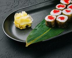 maki Sushi mit rot Kaviar auf schwarz Teller foto