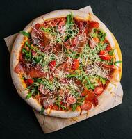 Italienisch Pizza mit Prosciutto, Rucola und Tomaten foto