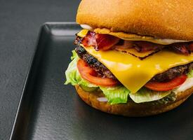 Speck Burger mit Rindfleisch Pastetchen auf schwarz Tablett foto