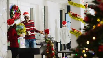 Mitarbeiter im Weihnachten dekoriert Büro genießen Kaffee, reden Über Weihnachten Ferien Pläne. Frau tragen Santa claus Hut Beitritt andere Mitarbeiter Mitglieder nehmen Verschiebung brechen im multiethnisch Arbeitsplatz foto