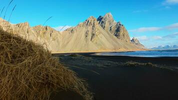 Arktis stokksnes schwarz Sand Strand mit fest Vestrahorn Berge Erstellen spektakulär isländisch Landschaft. majestätisch Ozean Küste mit Hügel auf Halbinsel im Island. Handheld Schuss. foto