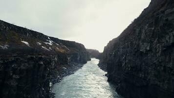 Drohne Schuss von isländisch gullfoss Kaskade, majestätisch Wasser Strom fließend zwischen felsig Hügel und Klippen. schön Wasserfall im Island Laufen Nieder aus Berge, Winter Landschaft. schleppend Bewegung. foto