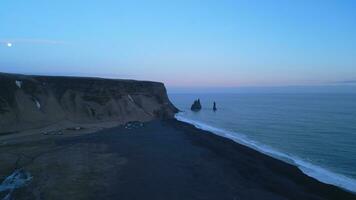 Drohne Schuss von reynisfjara Strand Landschaft auf atlantisch Ufer, spektakulär schwarz Sand Strand im Island. fest Hügel reynisfjall Berg Erstellen Fantastisch Horizont und Landschaft. schleppend Bewegung. foto