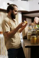 Mann im Null Abfall Geschäft nehmen Zeit zu analysieren Saft, Herstellung sicher es ist gemacht von organisch Früchte. Kunde gründlich Überprüfung Essen Artikel sind sicher im ökologisch verantwortlich lokal Supermarkt foto