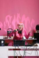 Musiker Stehen beim dj Tabelle halten Mikrofon reden mit Fans während spielen Techno Lied mit Fachmann Rührgerät Konsole. asiatisch Künstler mit Rosa Haar genießen zu ausführen Musik- beim Nacht im Verein foto