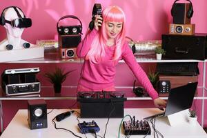 dj mit Rosa Haar spielen elektronisch Lied beim Fachmann Rührgerät Konsole Hören Musik- mit Headset, genießen Nachtleben. asiatisch Perfomer haben Spaß im Verein, dacing mit Fans während Performance foto