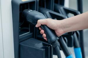 Laden ev Auto elektrisch Fahrzeug sauber Energie zum Fahren Zukunft. Hand halten Ladegerät Kopf Bahnhof. foto