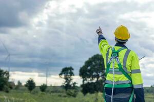 Ingenieur männlich Arbeiten im Wind Turbinen Bauernhof zurück Aussicht Hand zeigen beim das Himmel zum Zukunft von Öko sauber Energie Arbeiter Menschen foto