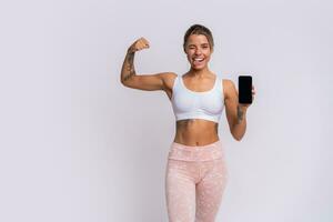 Ausbildung App. passen ziemlich Frau zeigen Smartphone mit modern Fitness Anwendung zum Verfolgung Sport Aktivität. posieren Über Gelb Studio Hintergrund. foto