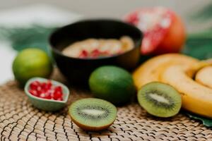 das Wesentliche zum Kochen Smoothie Schüssel. Blake Teller gekrönt mit Kiwi, Banane, Granatapfel Samen, Kalk, Granola, Chia Samen. gesund Frühstück. tropisch Stimmung. foto