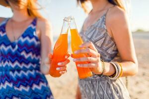 Sommer- Ferien und Ferien Konzept. freunde Trinken Limonade oder Alkohol , halten Getränk im Flaschen. genießen Sonnenuntergang auf das Strand. Party Zeit. Fokus auf Flasche. foto