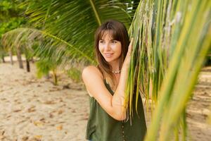 Sommer- Foto von natürlich Weiß Frau posieren auf das Strand in der Nähe von Palme Bäume.
