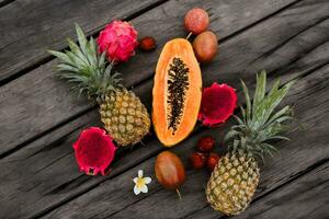 kreativ Komposition mit tropisch Früchte auf Holz Hintergrund, oben Sicht. Scheiben von Papaya, Drachen Obst und Ananas. foto