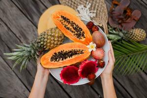 Frau Hände mit groß Teller von frisch exotisch Früchte foto