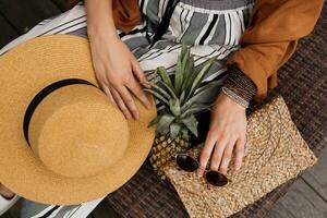 schließen oben Mode Einzelheiten von Bohemien Frau. Stroh Hut, Ananas und stilvoll Geldbeutel. foto