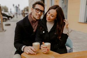 gut aussehend Mann und seine elegant Freundin umarmen und genießen heiß Getränk im Cafe . foto