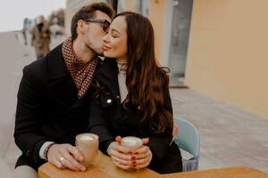 gut aussehend Mann und seine elegant Freundin umarmen und genießen heiß Getränk im Cafe . foto