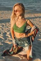 Sommer- Lebensstil Bild von blond Frau Zeichnung Aquarell Blume durch Bürste. Künstler Sitzung auf das Strand. Bohemien Outfit. foto