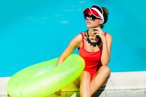 sexy Braun gebrannt Frau im rot Badeanzug haben Spaß und genießen Sommer- im tolle groß Schwimmen Schwimmbad. stilvoll transparent Deckel. Strand Party. foto