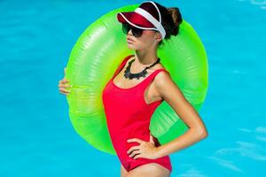 sexy Braun gebrannt Frau im rot Badeanzug haben Spaß und genießen Sommer- im tolle groß Schwimmen Schwimmbad. stilvoll transparent Deckel. Strand Party. foto