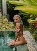 Herrlich blond Frau im sinnlich Badebekleidung posieren in der Nähe von Schwimmbad auf Luxus tropisch Villa. foto