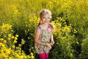 lustiges kleines Mädchen unter gelben Wildblumen foto