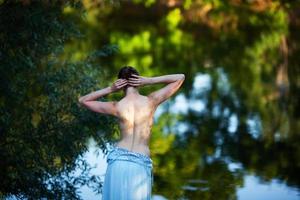 junge Frau zieht sich aus, bevor sie im See schwimmt foto