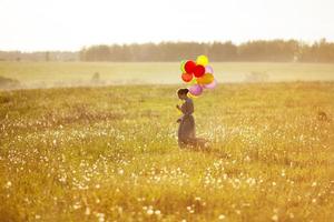 junge glückliche Frau mit Luftballons in einem Feld foto