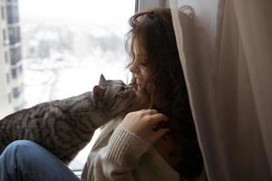 Mädchen sitzt und streichelte mit einer Katze foto