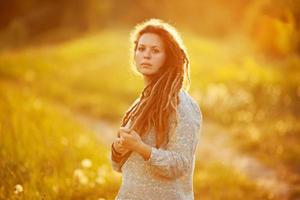 Mädchen mit Dreadlocks steht mitten auf der Wiese foto