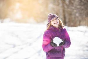 fröhliches Mädchen mit Schnee in den Händen foto