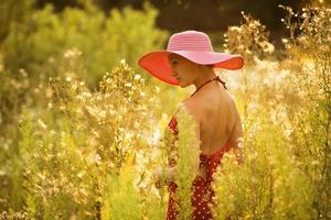 schöne Frau geht zwischen hohen Wildblumen foto