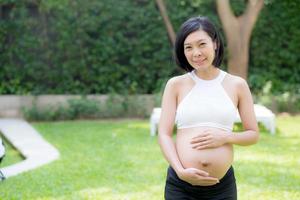 Schwangere der asiatischen jungen Frau des Porträts entspannen sich im Park. foto