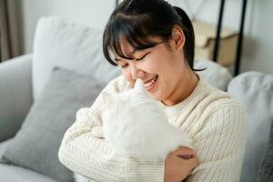 glücklich Frau spielen mit Katze im gemütlich Leben Zimmer beim heim. foto